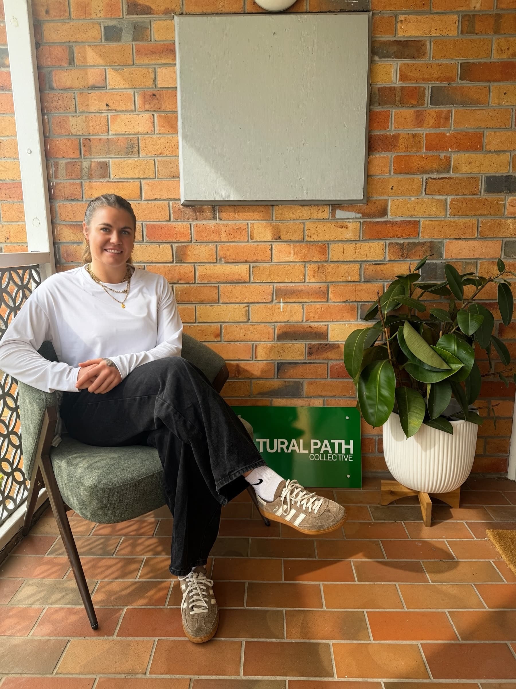 Alanna Cottrill seated at the entrance to The Natural Path Collective in Hamlyn Heights